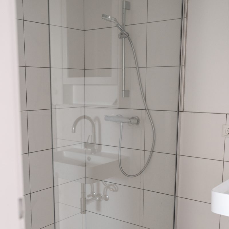 Helles Badezimmer mit gefliester Dusche und Glasabtrennung